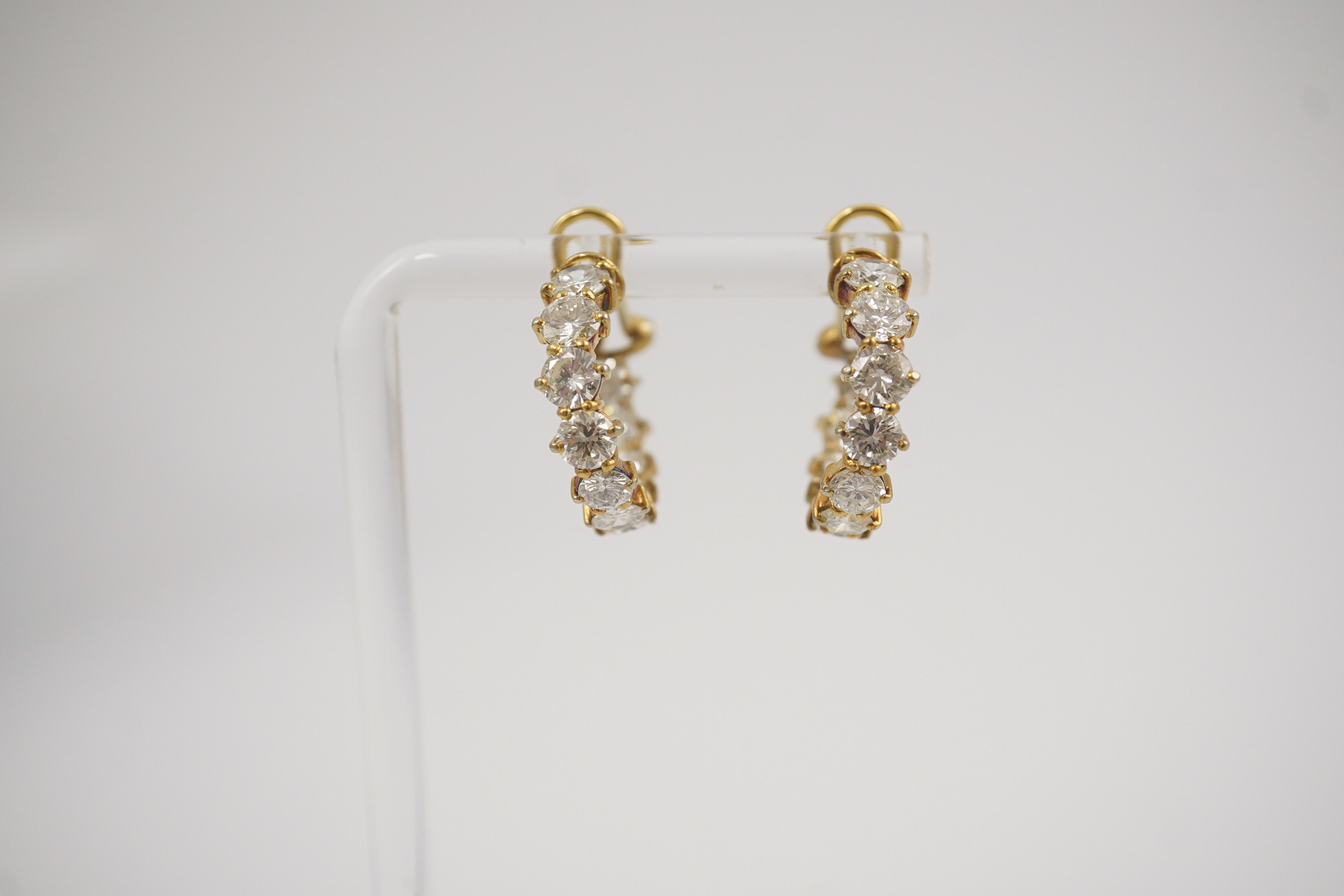 A modern pair of 18ct gold and graduated eleven stone round brilliant cut diamond set hoop earrings